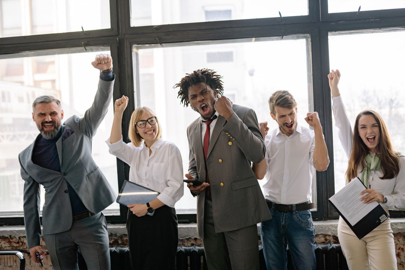 Une équipe lève les bras pour fêter une réussite dans un bureau lumineux